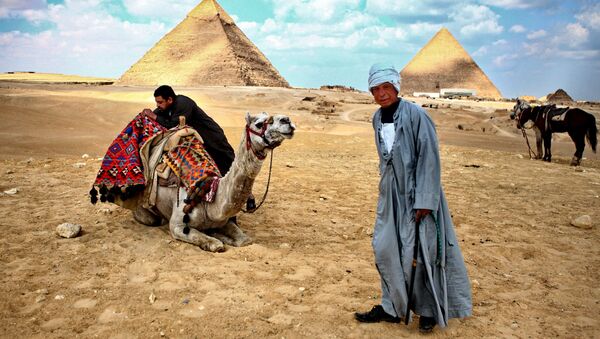 Местные жители стоят у пирамид в Гизе
