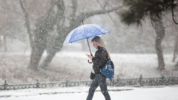 Девушка с зонтом во время снегопада на одной из улиц Симферополя