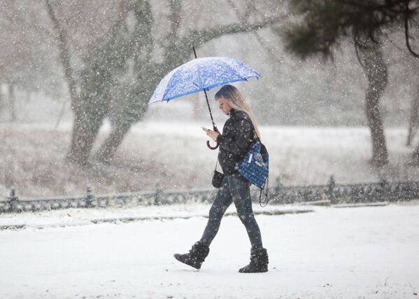 Девушка с зонтом во время снегопада на одной из улиц Симферополя