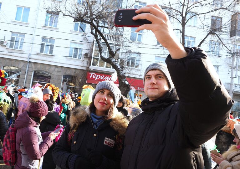 Зрители фотографируются на фоне праздничного шествия Дедов Морозов, Снегурочек и сказочных персонажей в Краснодаре