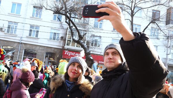 Зрители фотографируются на фоне праздничного шествия Дедов Морозов, Снегурочек и сказочных персонажей в Краснодаре
