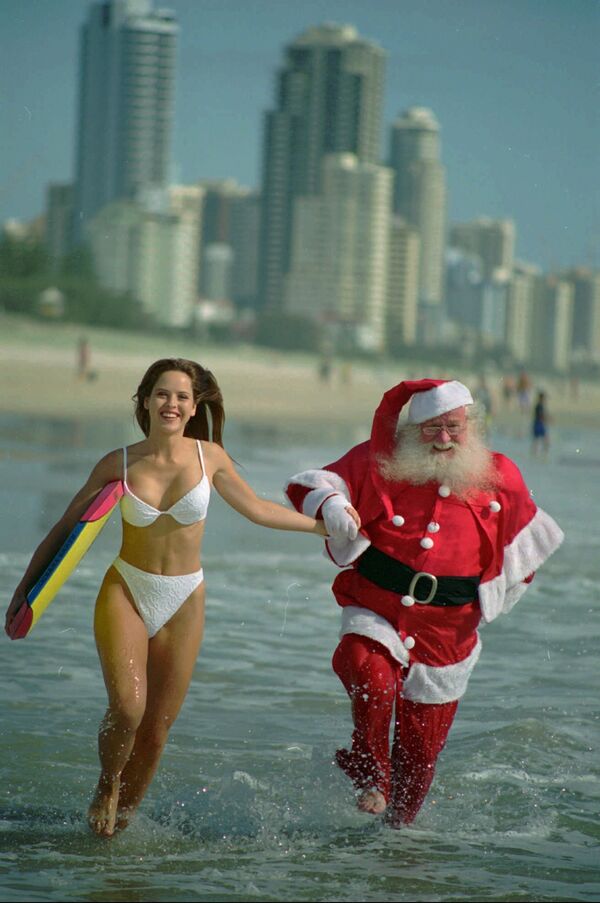 Девушка с доской для серфинга и Санта Клаус в Австралии