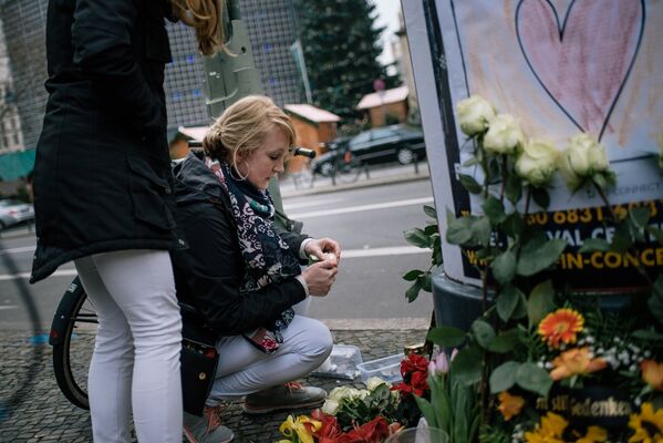 Девушка зажигает свечу недалеко от места теракта в Берлине. 20 декабря 2016