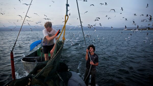 Международные волонтеры работают на рыбацкой лодке в Галилейском море, Израиль