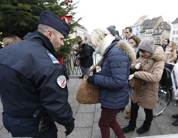 Сотрудник полиции проверяет сумки у посетителей рождественского базара в Страсбурге, Франция