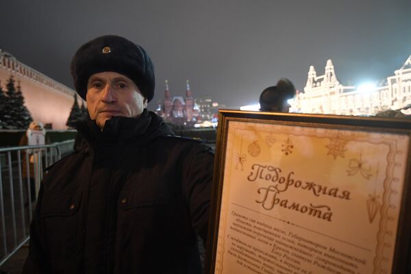Сотрудник правоохранительных органов демонстрирует подорожную грамоту для проезда специального автопоезда с главной Новогодней елкой России на территорию московского Кремля