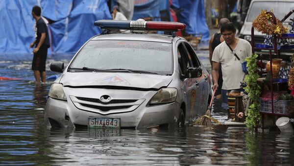 Полицейский автомобиль на улице, затопленной в результате тайфуна Нок-тен на Филиппинах