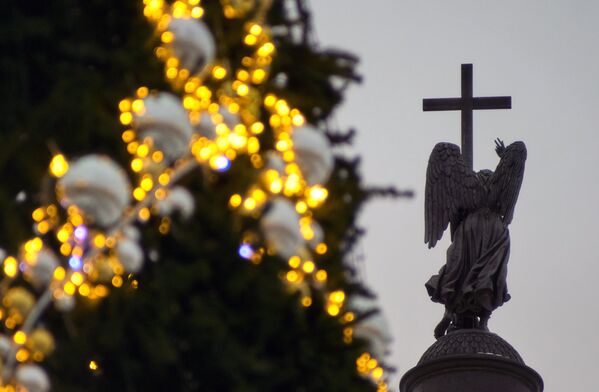 Новогодняя елка и статуя ангела на вершине Александровской колонны на Дворцовой площади в Санкт-Петербурге