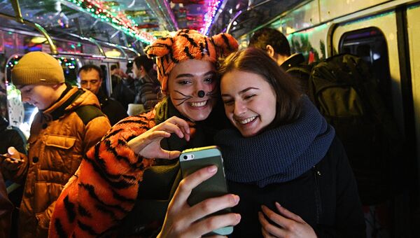 Пассажиры фотографируются в новогоднем поезде Московского метро, украшенном гирляндами и еловыми ветками