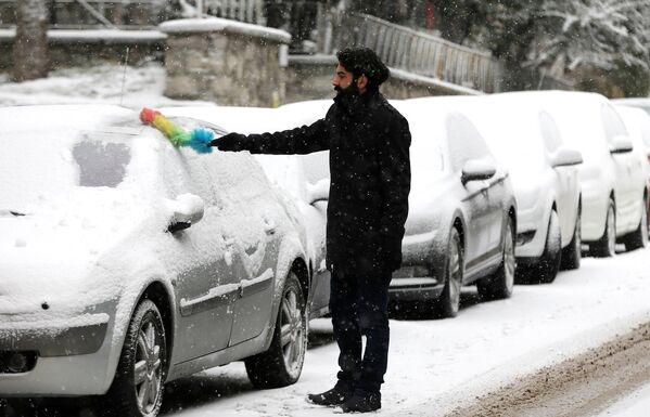 Мужчина чистит машину от снега в Анкаре