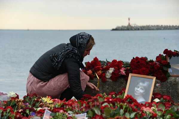 Женщина зажигает свечу в память о жертвах крушения самолета ТУ-154 в Сочи