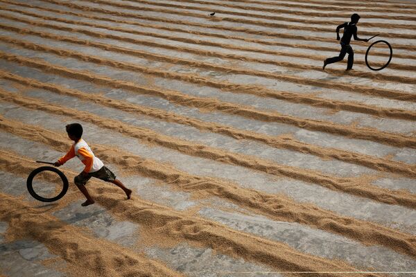 Дети играют с велосипедными шинами на рисовой фабрике, Бангладеш