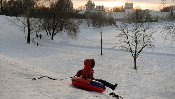Ребенок катается с горы на берегу Большого Новодевичьего пруда в Москве