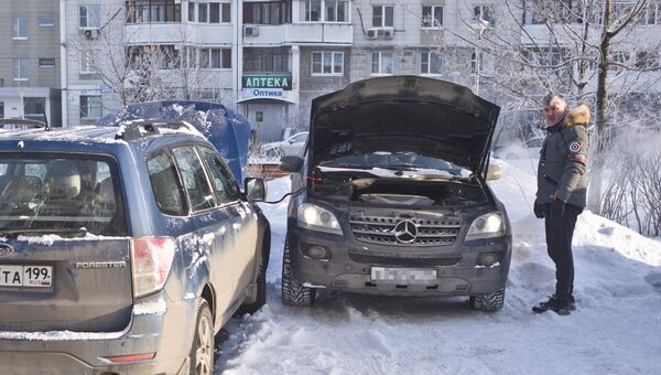Автомобилист заряжает аккумулятор своего автомобиля в Москве