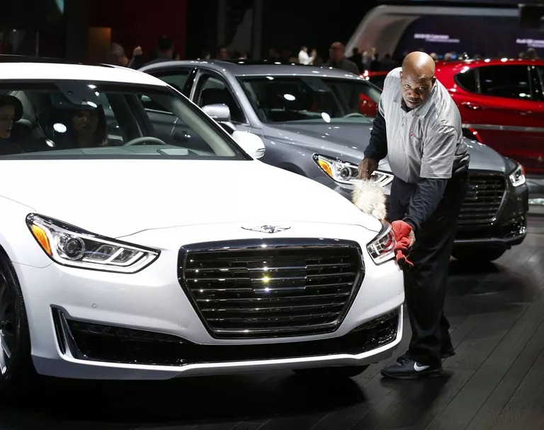 Сотрудник протирает автомобиль Hyundai Genesis на автосалоне в Детройте Сотрудник протирает автомобиль Hyundai Genesis на автосалоне в Детройте