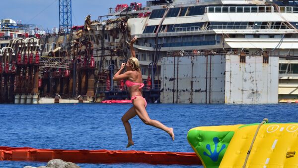 Девушка прыгает в воду недалеко от места крушения круизного судна Коста Конкордия
