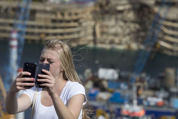 Девушка делает селфи на фоне потерпевшего крушение круизного судна Коста Конкордия