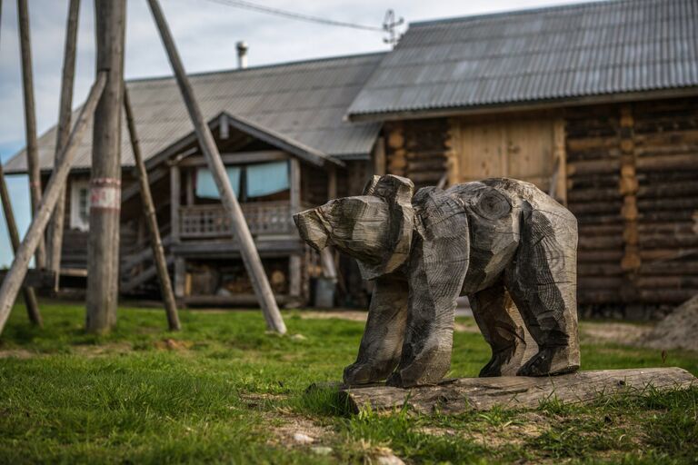 Деревянная фигура медведя на детской площадке в деревне Кинерма в Карелии