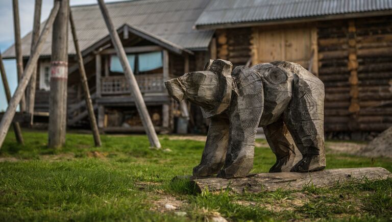 Деревянная фигура медведя на детской площадке в деревне Кинерма в Карелии