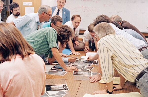 Члены научной команды Вояджерсмотрят свежие снимки Тритона спутника Нептуна, сделанные Вояджер-2. Август 1989 года