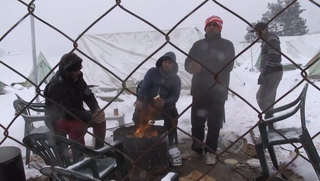 Беженцы грелись у костра в занесенном снегом лагере мигрантов в Салониках