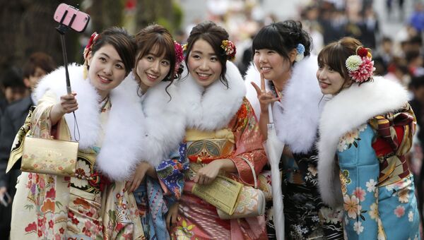 Девушки в кимоно делают селфи на Дне совершеннолетия в Токио. Архивное фото