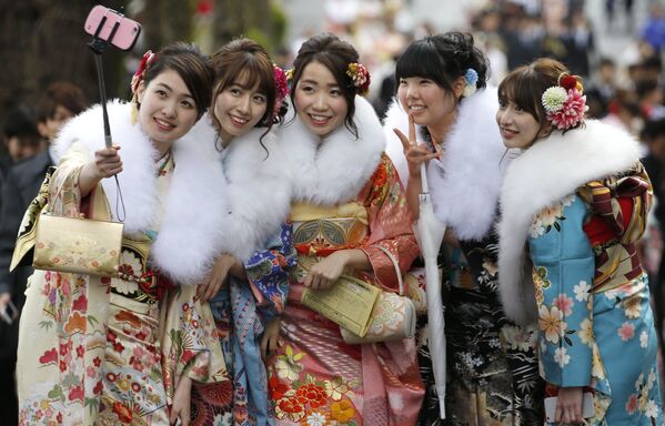 Девушки в кимоно делают селфи на Дне совершеннолетия в Токио