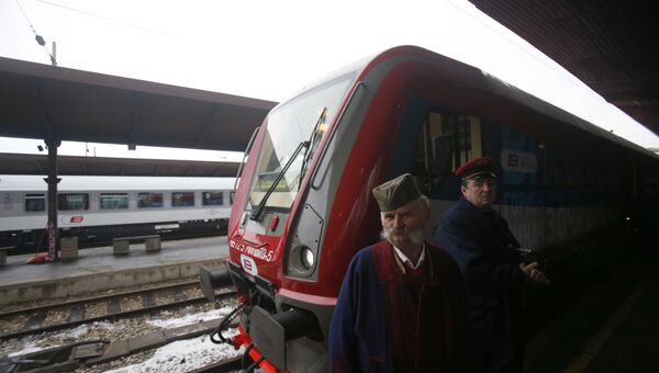 Мужчина в национальном сербском костюме у пассажирского поезда, следующего из Белграда в Косово
