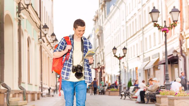 Молодой человек с камерой и картой города