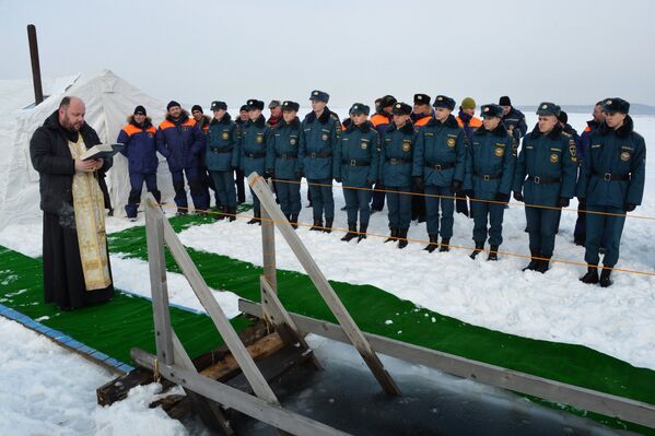 Священнослужитель освящает крещенскую купель, подготовленную сотрудниками МЧС РФ, на льду Амурского залива во Владивостоке