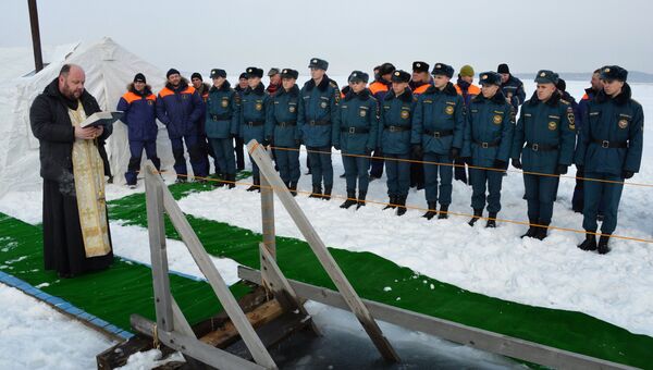 Священнослужитель освящает крещенскую купель, подготовленную сотрудниками МЧС РФ, на льду Амурского залива во Владивостоке