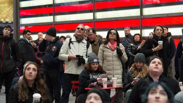 Люди смотрят трансляцию инаугурации Дональда Трампа на Таймс-сквер в Нью-Йорке. 20 января 2017 года