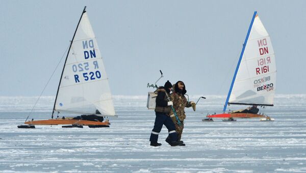 Рыбаки (на первом плане) и участники открытых соревнований по буерному спорту на кубок командующего Тихоокеанским флотом на льду Амурского залива во Владивостоке