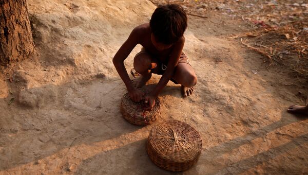 Мальчик закрывает корзину для змей в поселении заклинателей змей Jogi Dera в штате Уттар-Прадеш, Индия