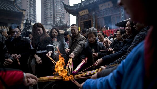 Люди молятся с ароматическими палочками в храме Шанхая. 28 января 2017 года
