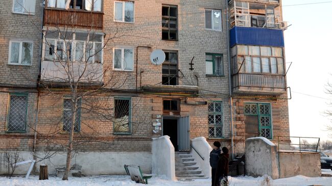 Местные жители у жилого дома в городе Докучаевск Донецкой области, пострадавшего в результате обстрела украинскими силовиками.