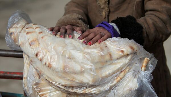 Женщина держит лепешки в городе Алеппо
