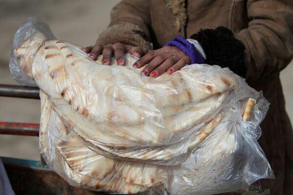 Женщина держит лепешки в городе Алеппо