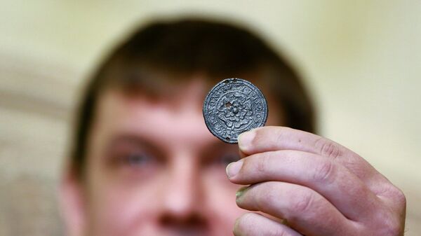 Руководитель Департамента культурного наследия Алексей Емельянов демонстрирует медальон XVI века, найденный во время археологических работ в парке Зарядье