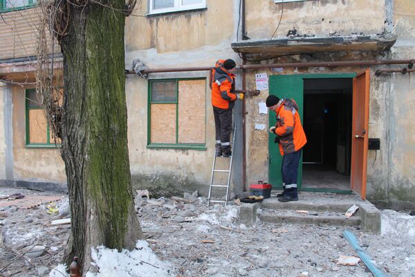 Сотрудники коммунальных служб проводят работы у дома, пострадавшего в результате обстрела украинскими силовиками, в Донецке. 1 февраля 2017