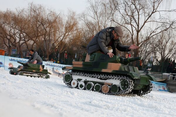 Люди катаются на электрических игрушечных танках в парке Таожаньтин в последний день китайского Нового года в Пекине, Китай