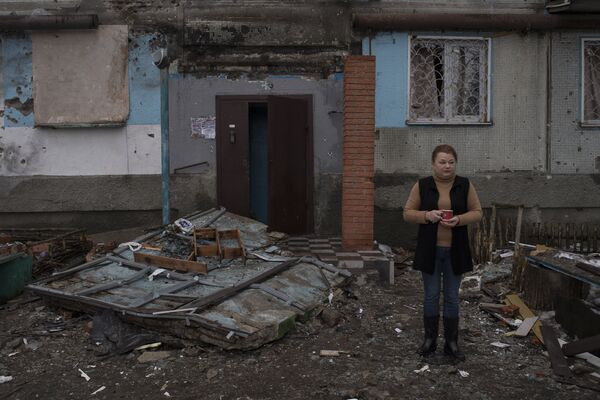 Женщина у входа в поврежденное в результате обстрелов здание в Киевском районе Донецка