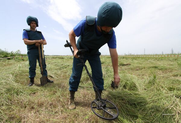Саперы МЧС ДНР обследуют с миноискателем участок поля в районе города Дебальцево
