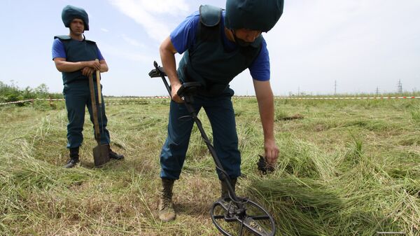 Саперы МЧС ДНР обследуют с миноискателем участок поля в районе города Дебальцево