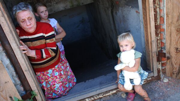 Дети и женщина, живущие в бомбоубежище в одном из окраинных районов Донецка, продолжающих подвергаться обстрелам со стороны украинских силовиков