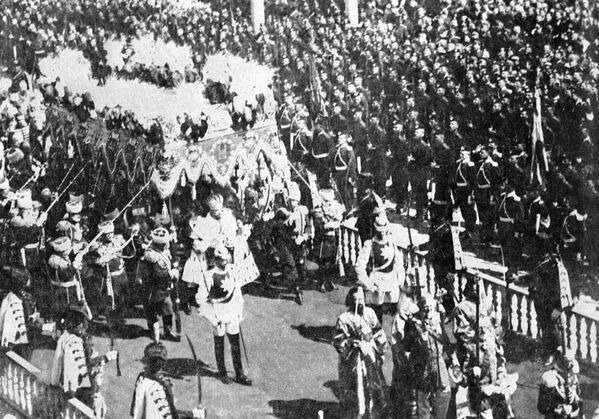 Николай II в царской мантии с короной, скипетром и жезлом шествует под балдахином в Кремле