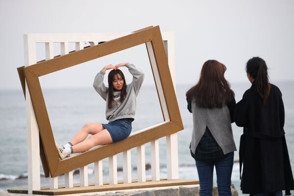 Девушки фотографируются на пляже Gyeongpo Beach в городе Каннын, Республика Корея