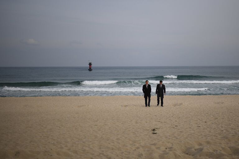 Мужчины в деловых костюмах на пляже Gyeongpo Beach в городе Каннын, Республика Корея