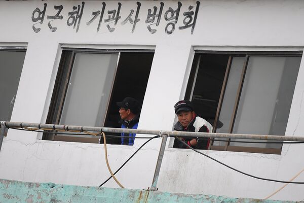 Мужчины на причале рыболовных судов в городе Jumulli, Республика Корея