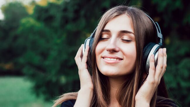 Девушка слушает музыку в наушниках. Архивное фото